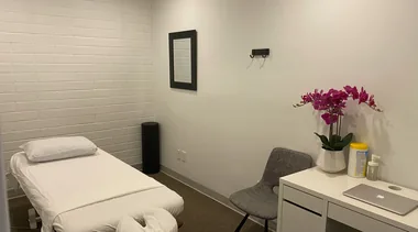 Sala de atendimento estético preparada, com maca, cadeira e bancada